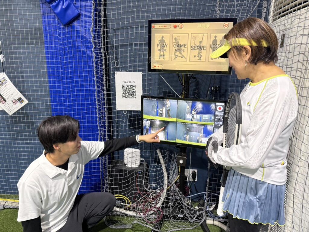 コーチと一緒にモーションリプレイでフォームを確認する様子